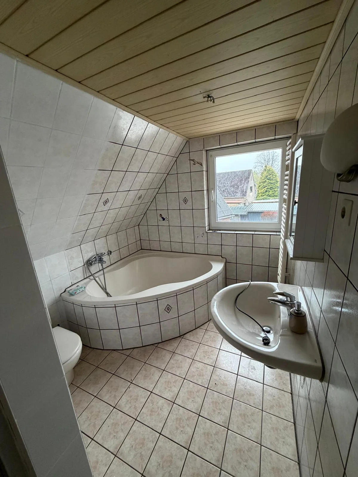 Gefliestes Badezimmer mit Eckbadewanne und Waschbecken