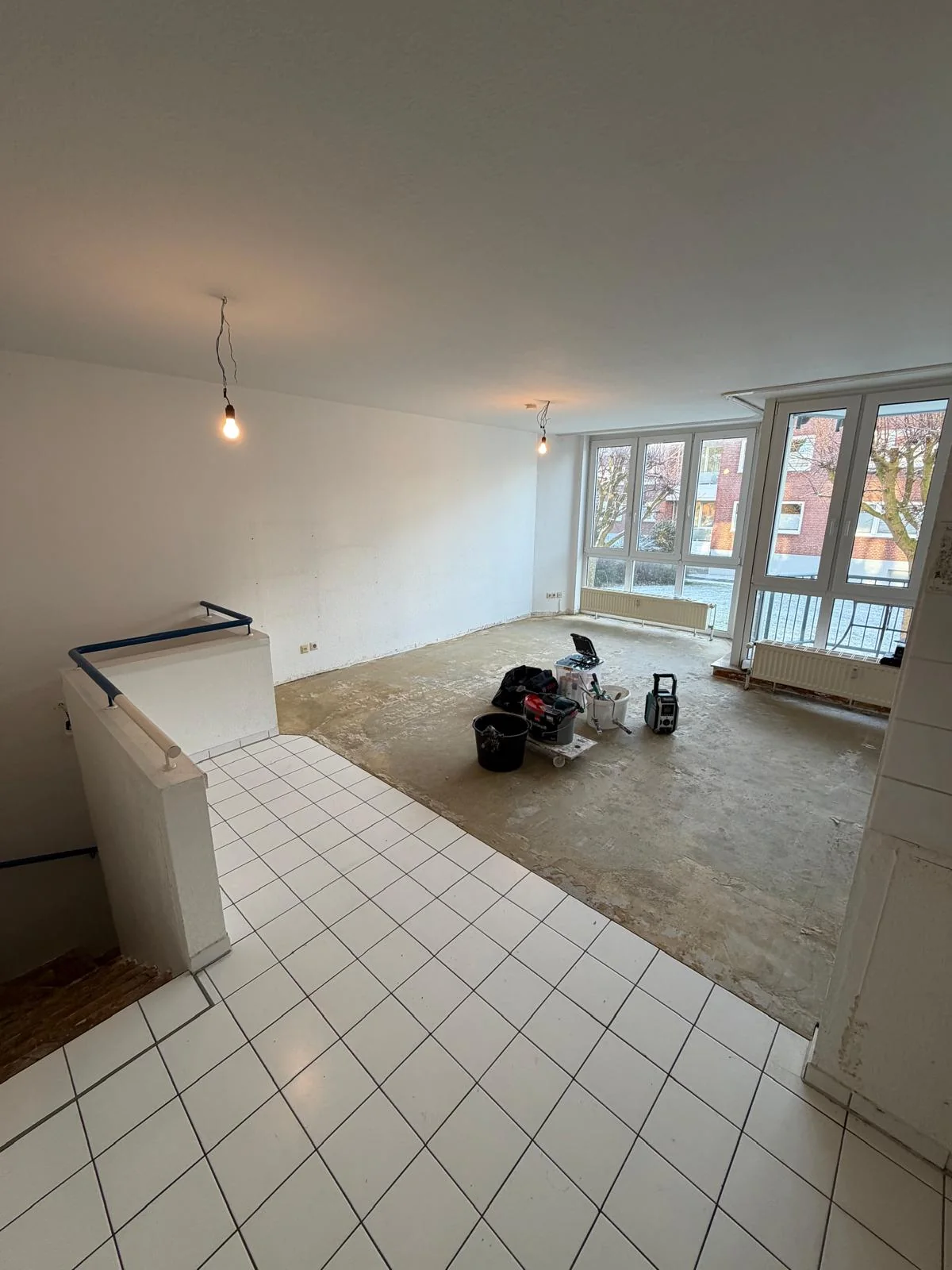 Wohnraum mit teilweise entfernten Bodenbelägen und Arbeitsmaterial
